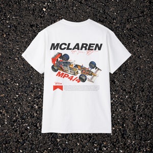 May include: White t-shirt featuring a red, white and black McLaren MP4/4 Formula One car graphic on the back. The text "McLaren" is printed in black above the car and "MP4/4" is printed in red below the car. The text "Vintage GT Club" is printed in red below the car graphic.