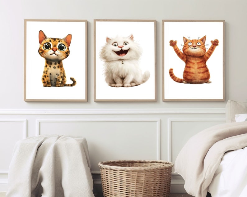 May include: Three framed art prints featuring cartoon cats. The first cat is spotted with large eyes. The second is a fluffy white cat with a wide grin. The third is an orange tabby with its arms raised. The prints are in light brown frames.