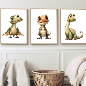 May include: Three framed illustrations of cartoon dinosaurs. The first dinosaur is green with wings and has a surprised expression. The second dinosaur is orange and green with a friendly expression. The third dinosaur is green with a long neck and a friendly expression.