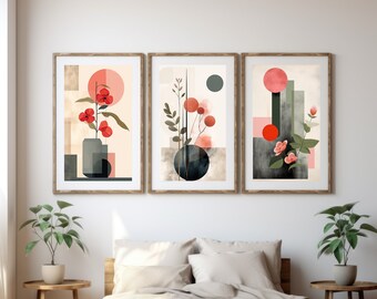 Peut inclure: Trois impressions d'art abstrait avec des formes géométriques et des éléments floraux dans des tons de rouge, rose, vert et noir. Les impressions sont encadrées dans du bois naturel et accrochées à un mur blanc au-dessus d'un lit avec une tête de lit et une literie en lin beige.