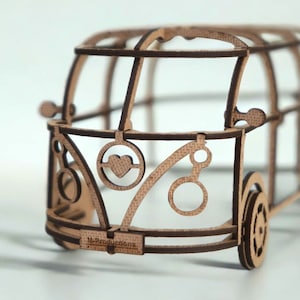 Könnte beinhalten: Ein Holzmodell eines Vintage Volkswagen-Busses mit einem Herz-Ausschnitt an der Vorderseite. Das Modell ist aus braunem Holz gefertigt und hat einen weißen Hintergrund.