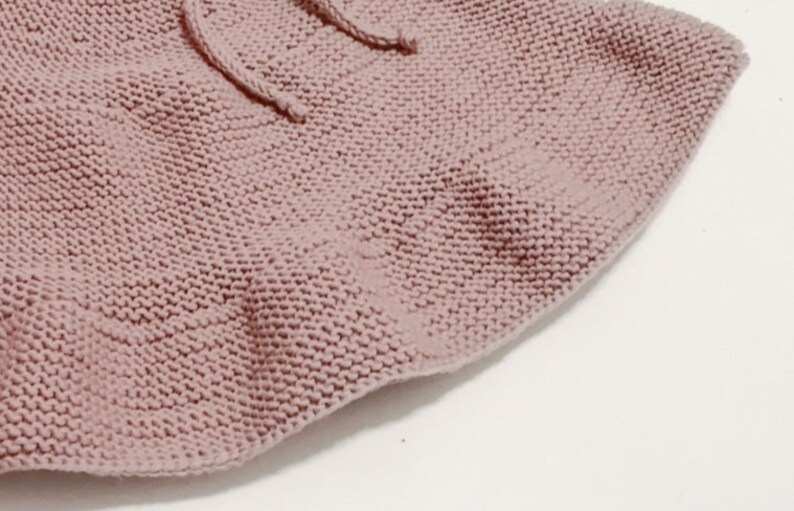 Puede incluir: Primer plano de una tela de punto suave y rosa con una textura delicada. La tela est&aacute; tejida en un patr&oacute;n de punto fino, creando una sensaci&oacute;n suave y acogedora.