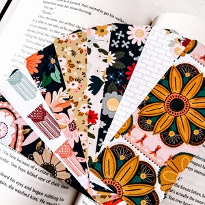 Op de afbeelding: Een verzameling kleurrijke bladwijzers met bloemen- en geometrische patronen. De bladwijzers zijn gemaakt van papier en hebben verschillende ontwerpen, waaronder bloemen, zonnebloemen en abstracte patronen.