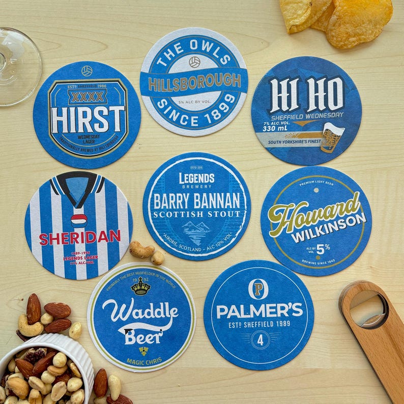 K&ouml;nnte beinhalten: Zehn runde blaue und wei&szlig;e Untersetzer mit verschiedenen Designs und Texten. Die Untersetzer zeigen Namen wie "Hirst", "Sheridan", "Waddle Beer", "Palmer's", "Howard Wilkinson", "Barry Bannan", "The Owls" und "Hi Ho".