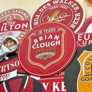May include: A collection of red, white, and black round coasters with various designs. The coasters feature the names "Peter Hilton", "Brian Clough", "Des Walker", and "European Cup".