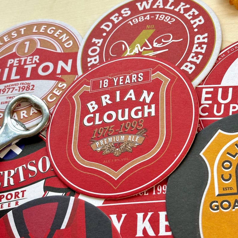 May include: A collection of red, white, and black round coasters with various designs. The coasters feature the names "Peter Hilton", "Brian Clough", "Des Walker", and "European Cup".