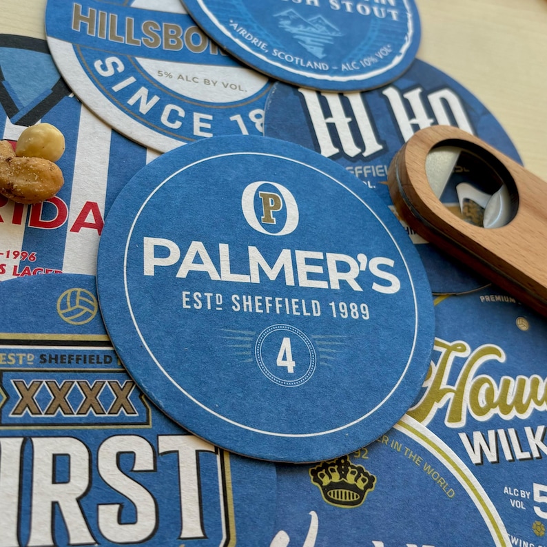 K&ouml;nnte beinhalten: Ein runder Untersetzer in Blau und Gold mit dem Text "Palmer's" und "Est. Sheffield 1989". Der Untersetzer hat ein gro&szlig;es "P" in einem Kreis oben links und die Nummer "4" in einem Kreis in der Mitte.