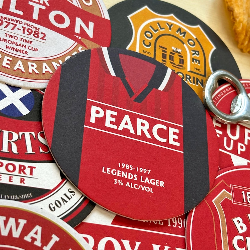 May include: A red and black beer coaster with a football jersey design. The jersey has the name "PEARCE" and the text "1985-1997 LEGENDS LAGER 3% ALC/VOL".