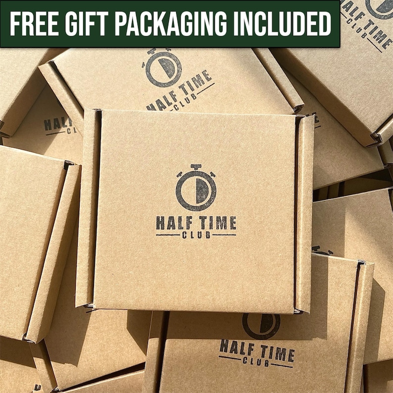 May include: Multiple brown cardboard boxes with the logo "Half Time Club" printed on them. The logo features a stopwatch with a black and white design. The text "FREE GIFT PACKAGING INCLUDED" is printed in green at the top of the image.
