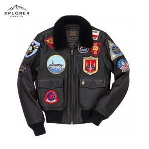 Può includere: Giacca bomber in pelle nera con diverse toppe ricamate. Presenta un colletto in pelliccia nera, una cerniera frontale, due tasche anteriori e polsini e orlo a coste. La giacca è in classico stile aviatore con toppe a tema militare.