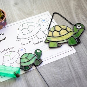 May include: A stained glass turtle suncatcher kit with instructions and tools. The kit includes a green and yellow stained glass turtle, a garden stake, and a suncatcher.