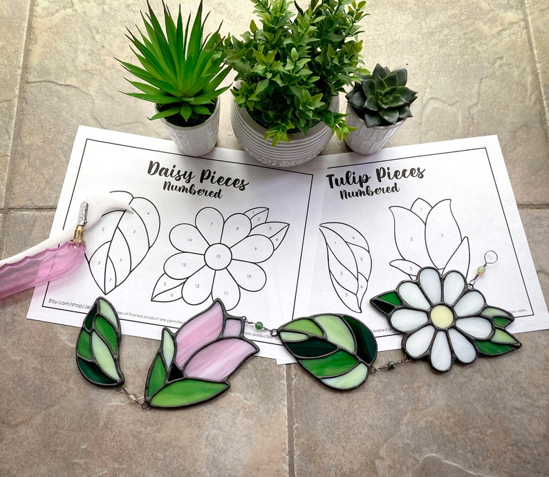 May include: Two stained glass craft kits, one with a daisy design and the other with a tulip design. Each kit includes numbered pieces of stained glass and a pattern sheet.