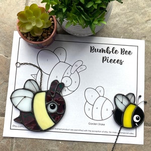 Op de afbeelding: Een tuinpaal van gekleurd glas met een zwart-gele hommel, met genummerde onderdelen om in elkaar te zetten. De afbeelding bevat een kleurgecodeerd diagram met de nummers 1 tot en met 11. De tekst "Bumble Bee Pieces" staat bovenaan de pagina. De tekst "Garden Stake" staat onder de hommel.