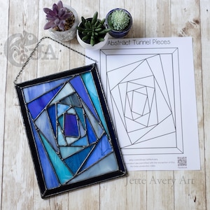 Op de afbeelding: Een rechthoekig glas-in-lood paneel met een geometrisch tunnelpatroon in tinten blauw, lichtblauw en wit, omlijst in donker metaal met een ophangketting, naast een papieren patroon met de tekst Abstract Tunnel Pieces.