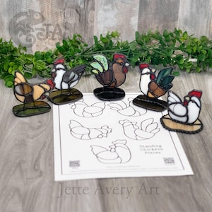 May include: A collection of stained glass chicken figurines in various colors, including brown, white, and red. Each chicken is mounted on a small base. A sheet of paper with chicken outlines is also present. The text "Standing Chickens Pieces" is visible.