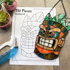 May include: A stained glass tiki face with a green and brown design. The face is numbered and ready to be assembled. The image includes the text "Tiki Pieces Numbered".