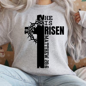 May include: A gray sweatshirt with a black cross and the text "He is Risen Matthew 28:6" printed on the front.