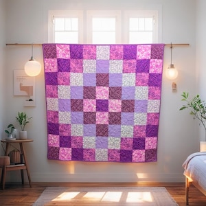 Peut inclure: Une courtepointe faite à la main avec un motif en damier dans les tons de violet, de lavande et de blanc. La courtepointe est exposée sur un mur, mettant en valeur son design complexe et sa texture matelassée. Les carrés présentent des motifs floraux et unis.