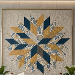 Op de afbeelding: Een grote, ingelijste quilt met een sterrenpatroon. De quilt heeft een combinatie van marineblauw, goud en stoffen met patronen. De achtergrond is een neutrale beige kleur met een gewatteerd patroon. De lijst is lichtgoud van kleur.