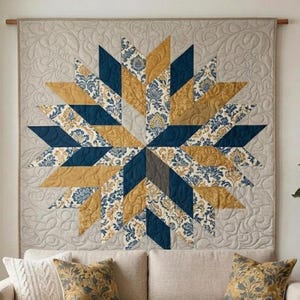 Op de afbeelding: Een grote, stervormige quilt wandophanging. De quilt heeft een centraal sterontwerp met afwisselende secties van marineblauw, goud en stof met patronen. De achtergrond is lichtbeige met een gewatteerd bloemmotief.