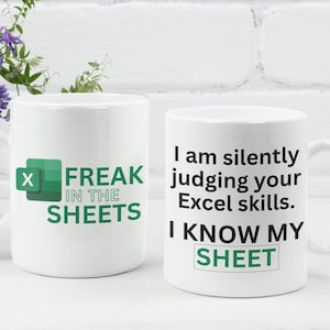 May include: Two white coffee mugs with green text and a green Excel logo. The mug on the left says "Freak in the Sheets". The mug on the right says "I am silently judging your Excel skills. I know my sheet".