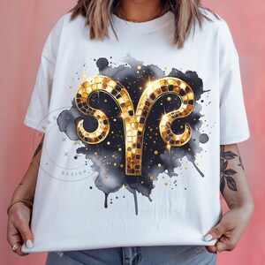 Könnte beinhalten: Weißes T-Shirt mit einem goldenen und schwarzen Aquarell-Design eines Widder-Sternzeichen-Symbols. Das Symbol besteht aus goldenen Mosaikfliesen.