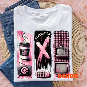 May include: White t-shirt with a pink and black graphic design featuring a coffee cup, a pink X with the word "GENERATION" above it, and two retro televisions. The design is set against a checkered background.