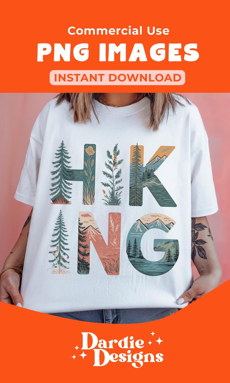 Op de afbeelding: Wit T-shirt met een grafisch ontwerp van het woord "HIKING" in kleurrijke letters. Elke letter is gevuld met een natuursc&egrave;ne, waaronder bomen, bergen en een meer. De tekst "DARDIE DESIGNS" staat onderaan het shirt.