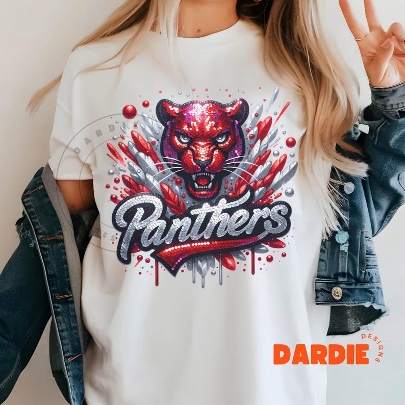 May include: White t-shirt with a red, white, and silver sequined design of a panther head and the word "Panthers". The design has a dripping effect with red and silver sequins.