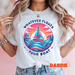 May include: White t-shirt with a colorful graphic of a sailboat on a sunset ocean scene. The text "Whatever Floats Your Boat" is written around the graphic.