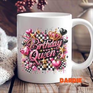 May include: White ceramic mug with a pink, black, and gold design featuring the words "Birthday Queen" and a crown. The design also includes hearts, stars, and checkered patterns.