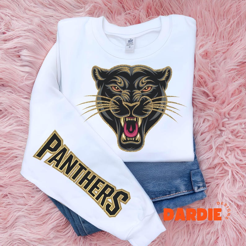 Pode incluir: Camisola branca com um gr&aacute;fico de pantera negra na frente e a palavra "PANTHERS" em glitter dourado na manga.