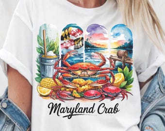 Könnte beinhalten: Weißes T-Shirt mit einer bunten Illustration eines Krabben, Maiskolbens, Zitronen und einem Glas Eistee. Die Illustration ist vor dem Hintergrund einer Wasserkulisse mit der Flagge des Bundesstaates Maryland. Der Text "Maryland Crab" ist unter der Illustration gedruckt.