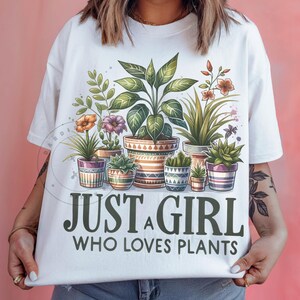 May include: White t-shirt featuring a graphic of potted plants and the text "Just a girl who loves plants".