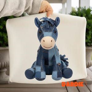 May include: A denim horse plush toy with a patchwork design in shades of blue. The toy has a light tan face, dark eyes, and a fringe mane. The word "DARDIE" is printed in orange at the bottom.