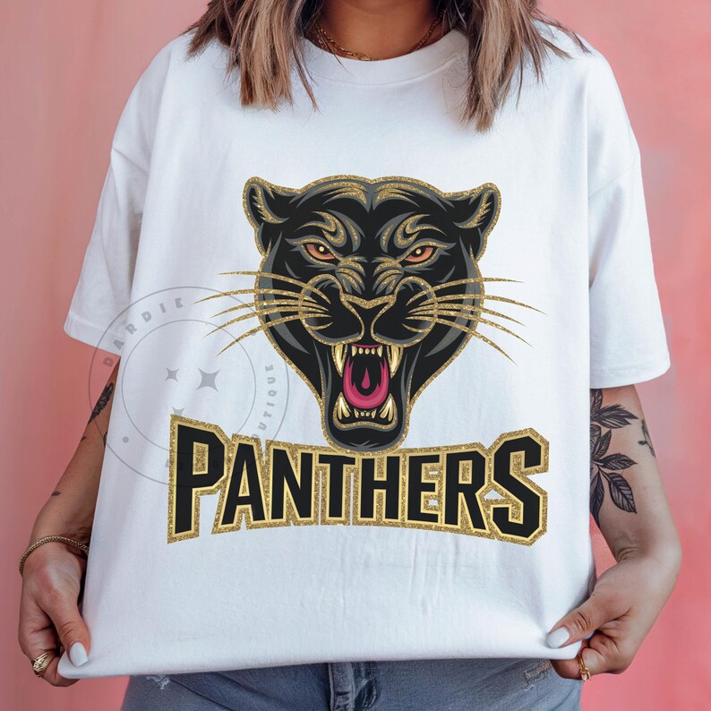 Pode incluir: Camiseta branca com um gr&aacute;fico de pantera negra e letras douradas com glitter que dizem "PANTHERS".