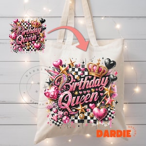 May include: A white canvas tote bag with a pink and black design featuring the words "Birthday Queen" in a glittery font. The design also includes a crown, hearts, and stars.