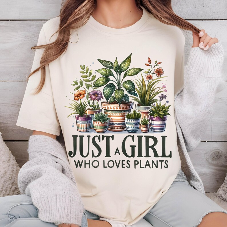May include: A cream-coloured t-shirt with a graphic of potted plants and the text "Just a girl who loves plants".