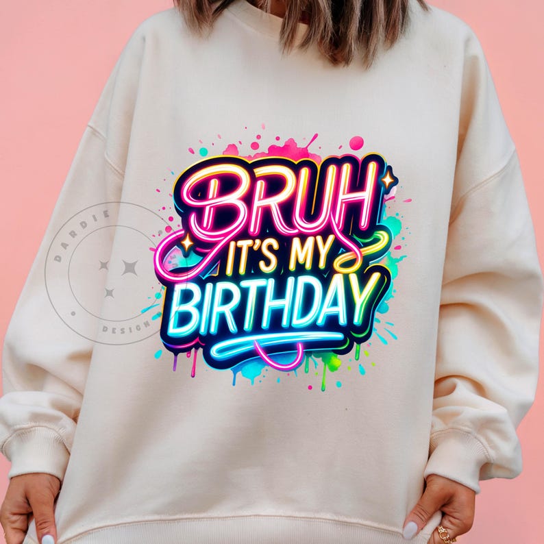 以下が含まれることがあります： ネオンの文字で「Bruh it's my birthday」と書かれたカラフルなグラフィックデザインが施された白いスウェットシャツです。