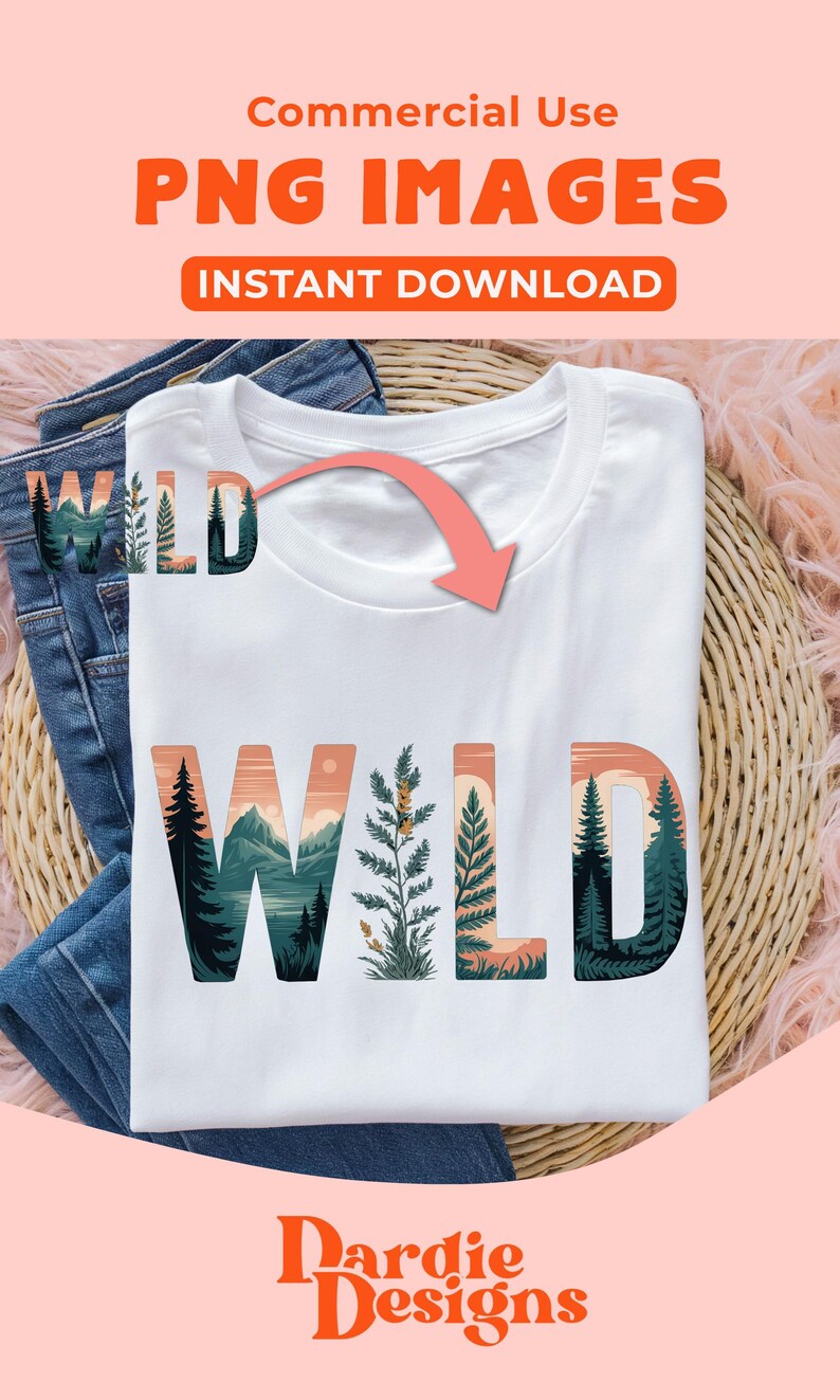 May include: White t-shirt with the word "WILD" in a nature-themed design. The letters feature illustrations of mountains, trees, and plants in shades of green, orange, and blue. The shirt is folded on top of blue jeans.