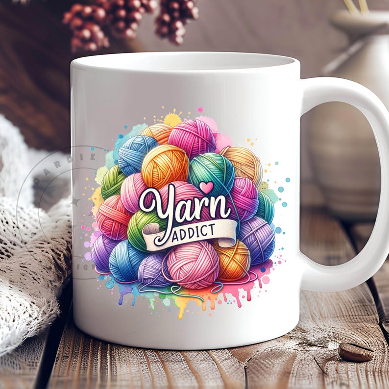 May include: White ceramic mug featuring a colorful design of yarn balls in various colors, with the text "Yarn Addict" in a decorative font. The design includes a heart and watercolor paint splatters.