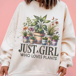 May include: A cream-coloured sweatshirt with a graphic of potted plants and the text "Just a girl who loves plants".