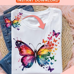 May include: A white t-shirt with a colorful watercolor butterfly design. The butterfly is surrounded by smaller butterflies in a rainbow of colors. The design is perfect for adding a touch of whimsy to any outfit.