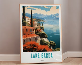 May include: A vintage travel poster featuring a colorful illustration of Lake Garda, Italy. The poster depicts a picturesque view of the lake with buildings and trees along the shoreline. The text "LAKE GARDA" and "ITALY" is displayed at the bottom of the poster.