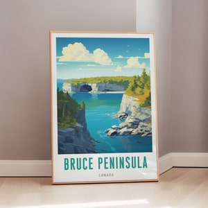 Könnte beinhalten: Ein gerahmter Kunstdruck mit einer malerischen Ansicht der Bruce-Halbinsel in Kanada. Das Kunstwerk zeigt eine türkisfarbene Bucht, umgeben von Klippen, üppigen grünen Bäumen und einem strahlend blauen Himmel mit flauschigen weißen Wolken. Der Text "BRUCE PENINSULA CANADA" ist unten abgedruckt.