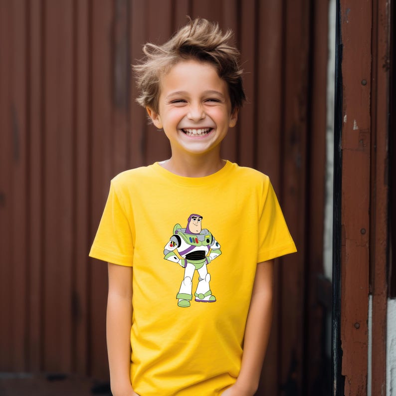 May include: A yellow t-shirt featuring a graphic of Buzz Lightyear from Toy Story. The character is depicted in his signature space ranger uniform with green, white, and purple accents. The shirt is worn by a smiling child.