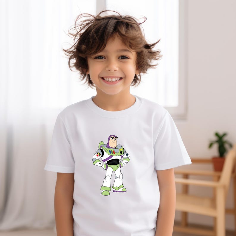 May include: White short-sleeved t-shirt featuring a colorful graphic of Buzz Lightyear from Toy Story. The character is depicted in his signature green, white, and purple spacesuit. The design is centered on the front of the shirt.