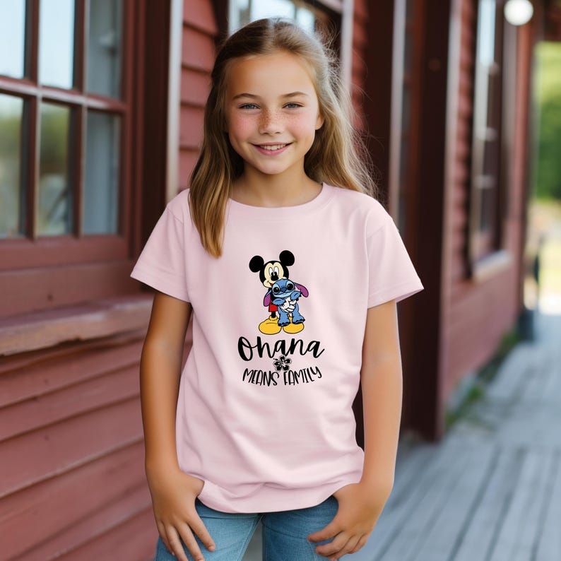 May include: A light pink t-shirt featuring a graphic of Mickey Mouse and Stitch. The text "Ohana means family" is printed below the characters. The shirt is worn by a young person.