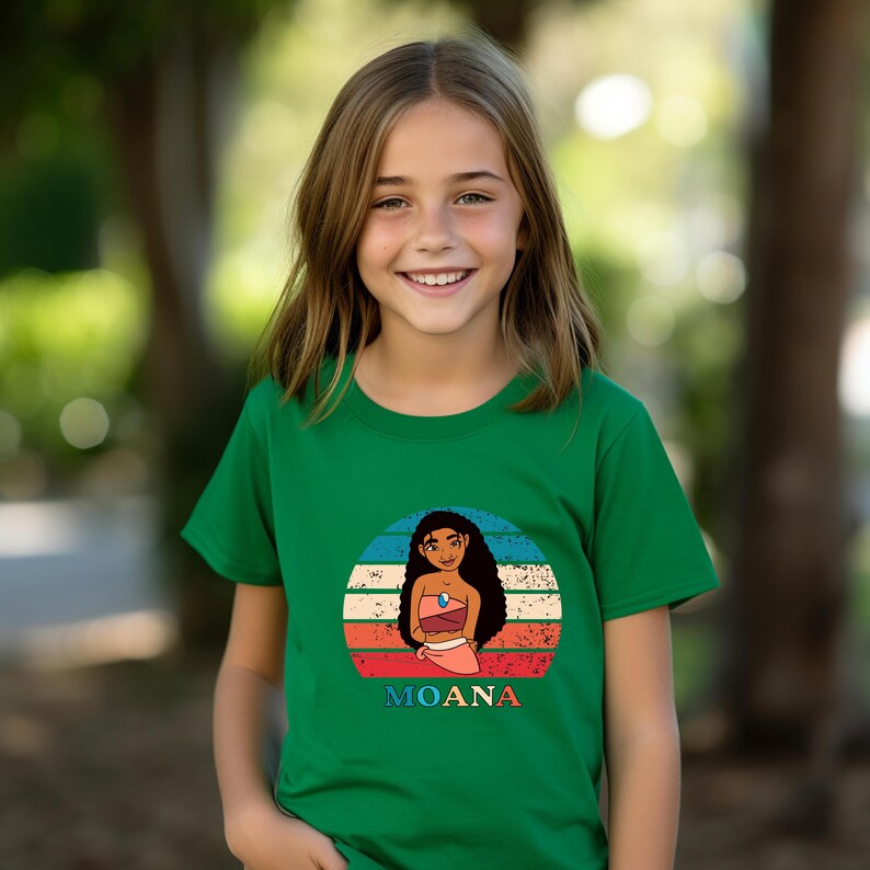 Puede incluir: Una camiseta verde con un gr&aacute;fico de estilo retro de Moana de la pel&iacute;cula de Disney Moana. El gr&aacute;fico presenta a Moana de pie frente a una puesta de sol con la palabra "Moana" escrita debajo.