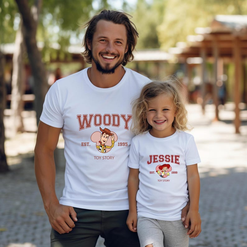 May include: White t-shirts with the text "WOODY" and "JESSIE" in red, along with cartoon images of the characters from Toy Story. The shirts also include the text "EST. 1995" and "EST. 1999" respectively, and the words "TOY STORY".